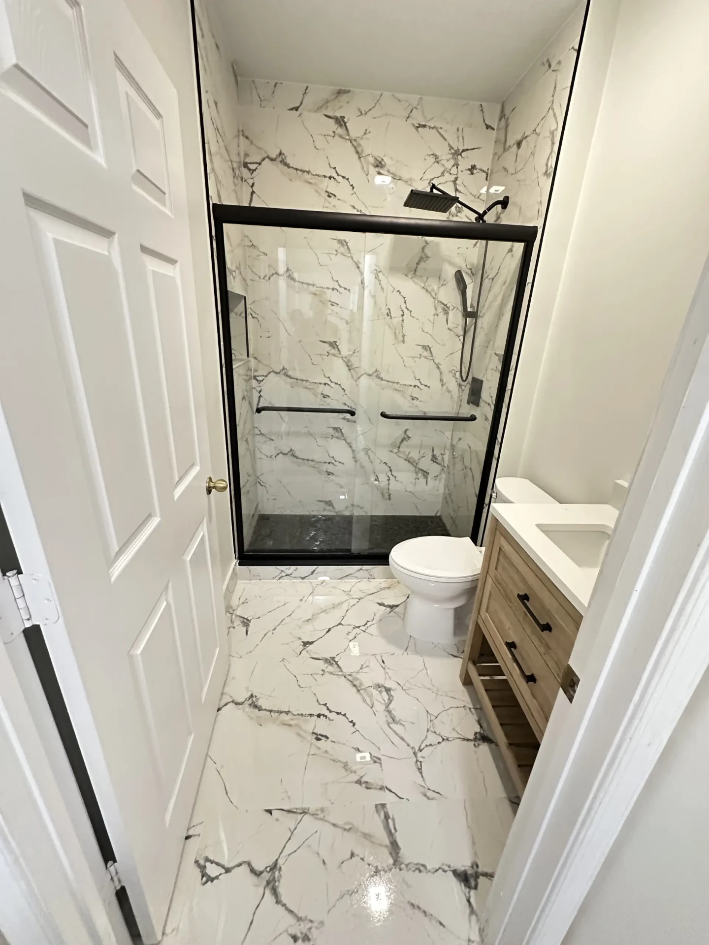 Completed walk-in shower with black frame glass door and marble tile